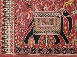 Red woven cloth with black elephants, yellow lions, and other decorations in white and red.
